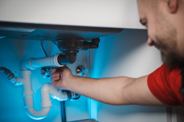 Professional plumber working on pipe installation in wall